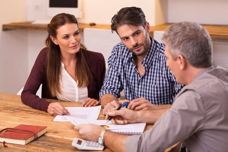 a businessman is explaining property investment terms and perception to a couple